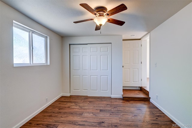 unfurnished bedroom featuring dark wood-type flooring, ceiling fan, a closet, and a textured ceiling