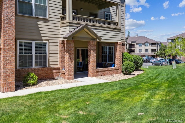12914 Ironstone Way Unit 102, Parker, CO 80134 - view of exterior entry featuring a balcony, brick siding, and a lawn