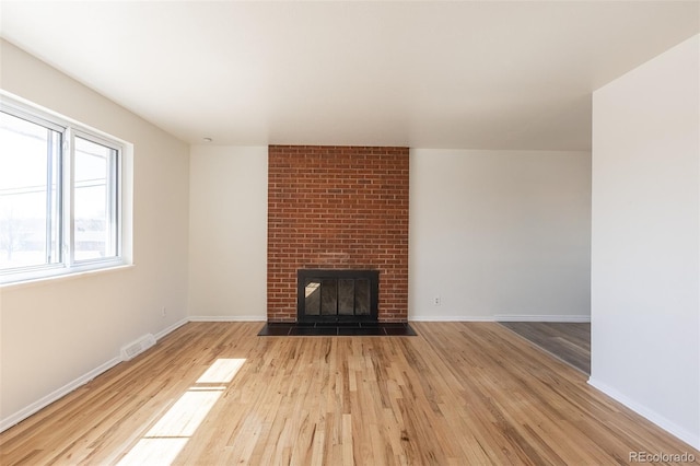 unfurnished living room featuring visible vents, baseboards, wood finished floors, and a fireplace