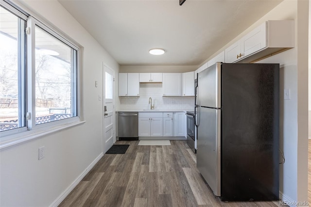 kitchen featuring white cabinetry, wood finished floors, tasteful backsplash, and appliances with stainless steel finishes