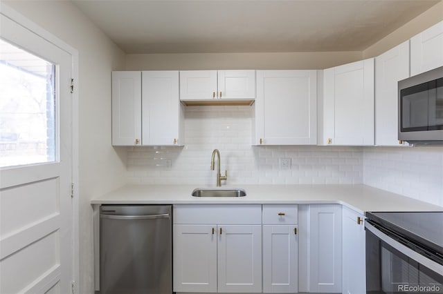 kitchen with a sink, stainless steel appliances, white cabinets, and light countertops