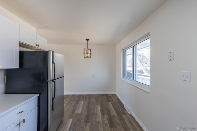 kitchen with visible vents, dark wood-type flooring, baseboards, freestanding refrigerator, and white cabinetry