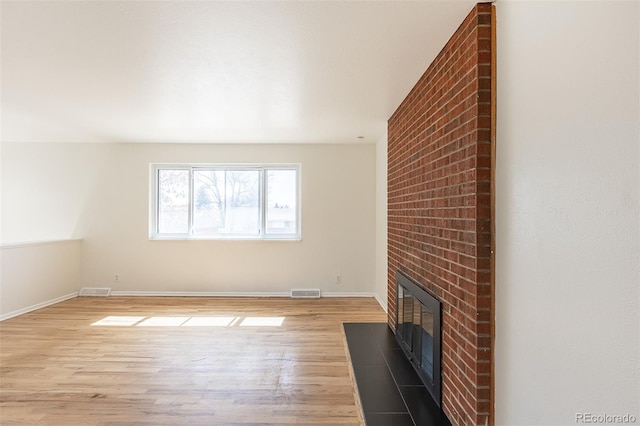 unfurnished living room featuring light wood-type flooring, baseboards, visible vents, and a fireplace