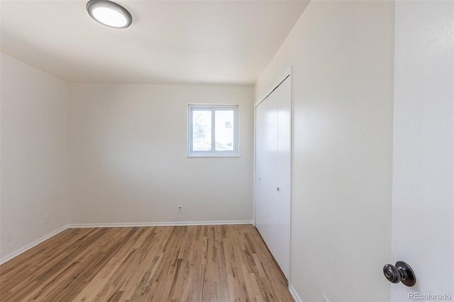 unfurnished bedroom featuring a closet, baseboards, and light wood-style floors