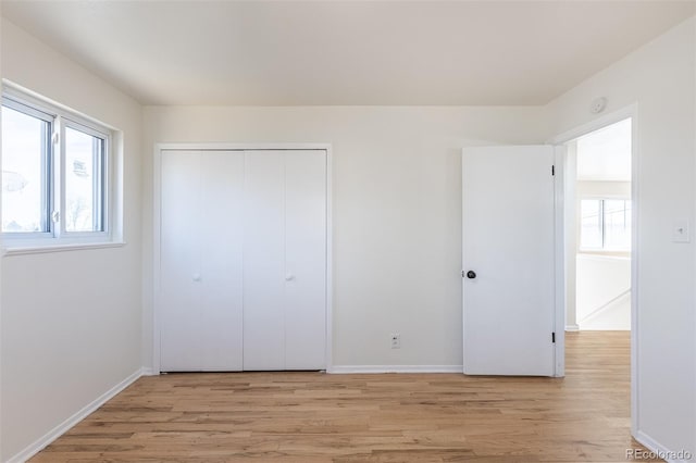 unfurnished bedroom featuring light wood-style floors, a closet, and baseboards