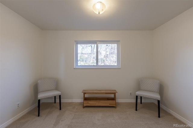 sitting room with baseboards and light carpet