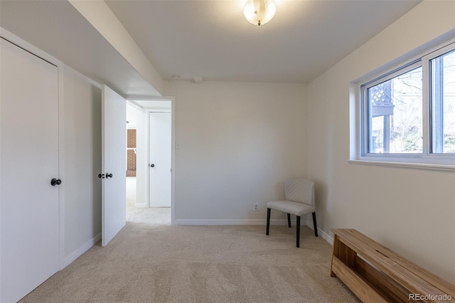 sitting room with baseboards and light carpet