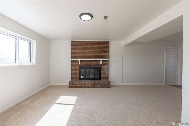 unfurnished living room with visible vents, a brick fireplace, baseboards, and carpet floors