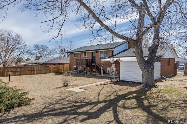 rear view of property with fence and brick siding