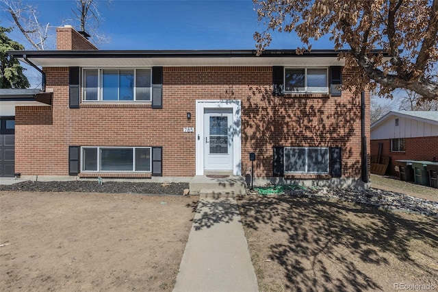 split foyer home featuring brick siding and a chimney