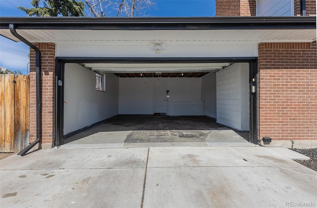 garage featuring driveway and fence