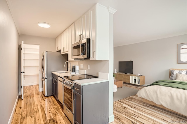 kitchen featuring white cabinetry, stainless steel appliances, sink, and light wood-type flooring