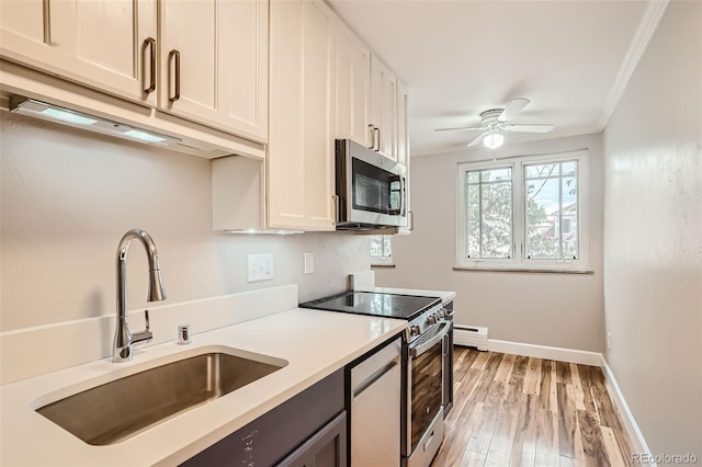 kitchen featuring sink, a baseboard heating unit, stainless steel appliances, and white cabinetry