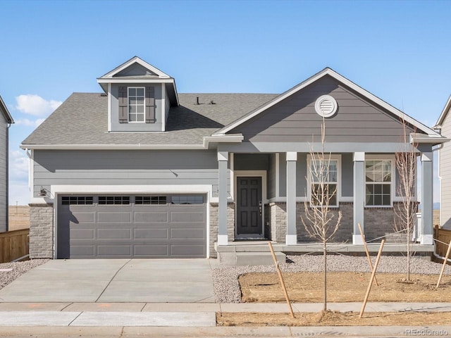 view of front of house with concrete driveway, stone siding, covered porch, a garage, and a shingled roof