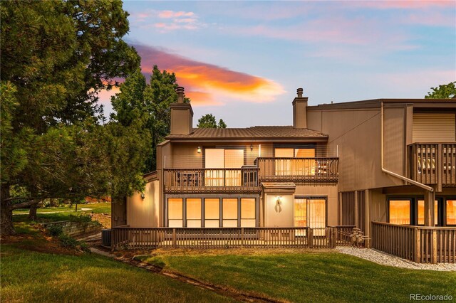 7300 W Stetson Pl Unit 46, Littleton, CO 80123 - back of property at dusk featuring a balcony, a chimney, a lawn, and central air condition unit