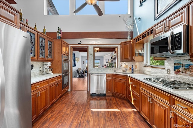 7300 W Stetson Pl Unit 46, Littleton, CO 80123 - kitchen featuring appliances with stainless steel finishes, a sink, ceiling fan, tasteful backsplash, and glass insert cabinets