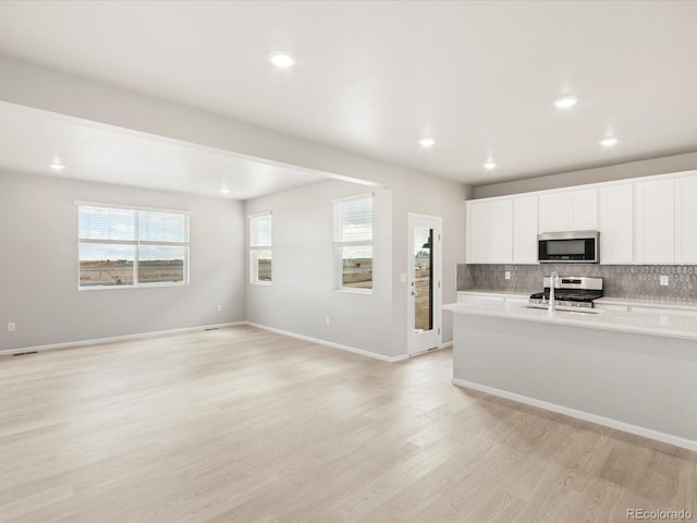 kitchen featuring light hardwood / wood-style floors, decorative backsplash, sink, white cabinetry, and stainless steel appliances