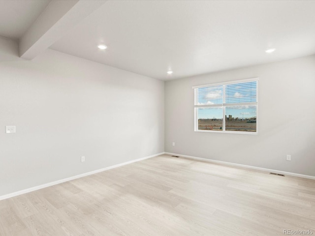 unfurnished room featuring beamed ceiling and light hardwood / wood-style floors