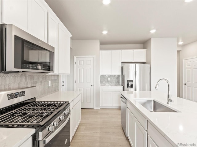 kitchen featuring decorative backsplash, sink, light stone countertops, stainless steel appliances, and white cabinets