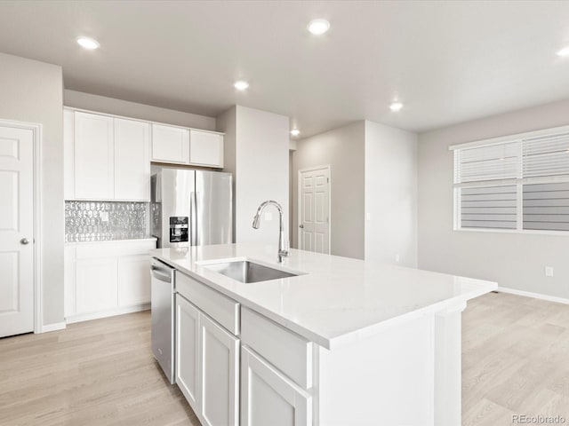 kitchen with white cabinetry, light hardwood / wood-style floors, an island with sink, appliances with stainless steel finishes, and sink