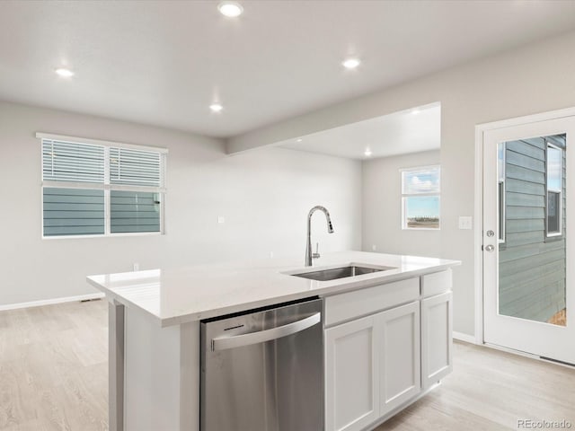 kitchen with stainless steel dishwasher, sink, white cabinetry, a kitchen island with sink, and light wood-type flooring