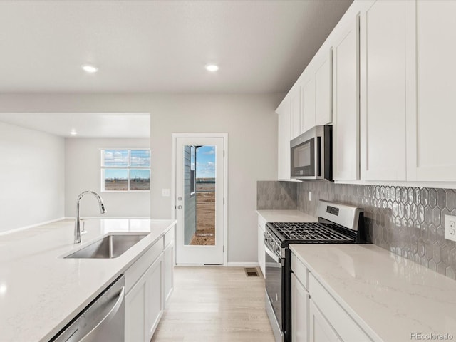 kitchen with white cabinets, sink, light stone counters, and stainless steel appliances