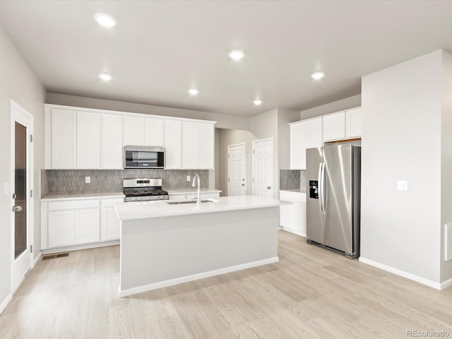 kitchen featuring sink, an island with sink, stainless steel appliances, and white cabinetry