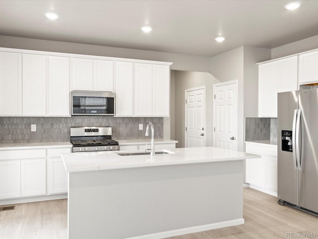 kitchen featuring white cabinets, light hardwood / wood-style flooring, stainless steel appliances, sink, and a center island with sink