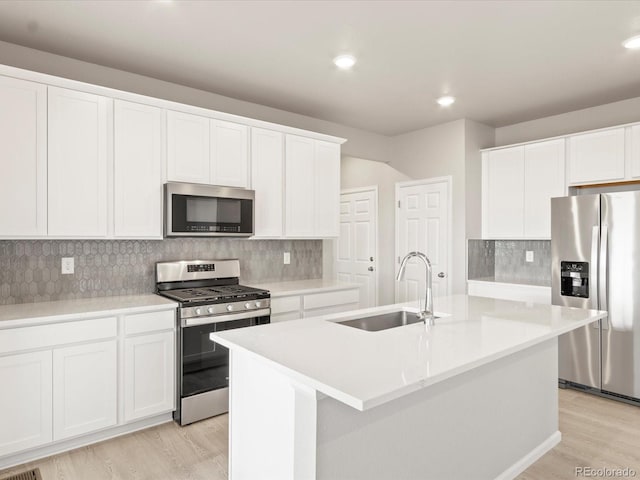 kitchen with stainless steel appliances, a kitchen island with sink, white cabinets, and sink