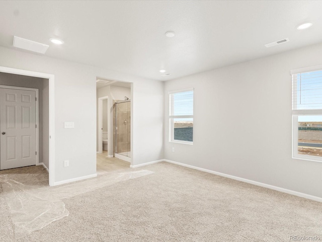 unfurnished bedroom featuring ensuite bathroom and light carpet