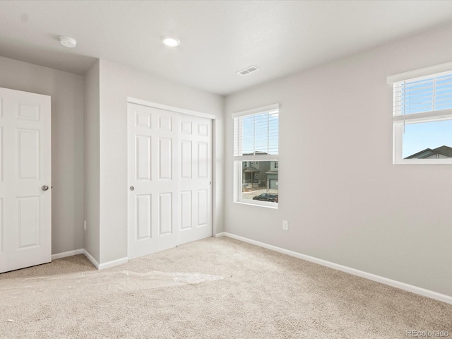 unfurnished bedroom featuring light colored carpet and a closet