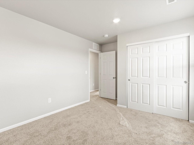 unfurnished bedroom with a closet and light carpet