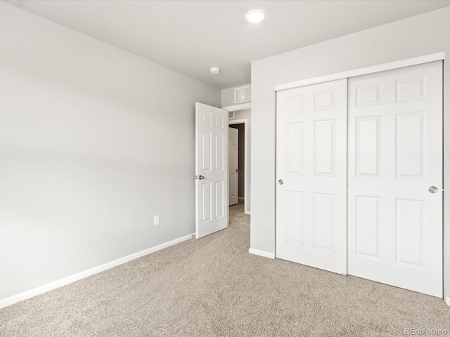 unfurnished bedroom featuring a closet and light colored carpet