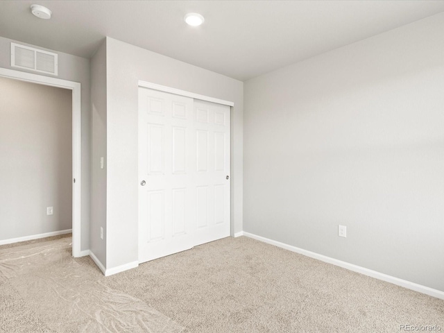 unfurnished bedroom with light carpet and a closet