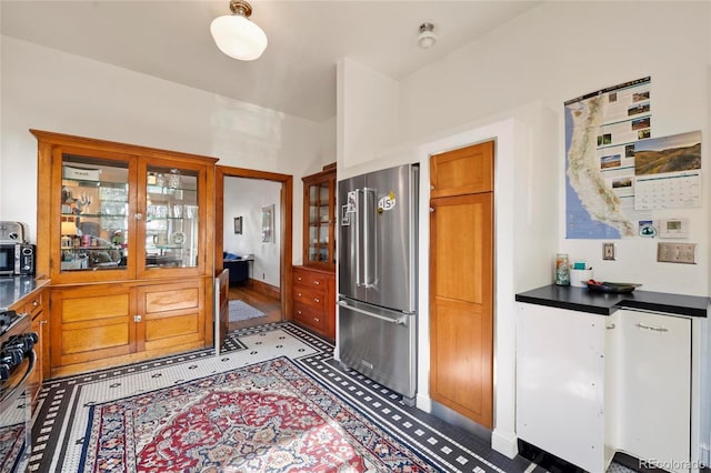 328 S Lincoln St, Denver, CO 80209 - kitchen with stainless steel appliances, glass insert cabinets, baseboards, brown cabinets, and dark countertops