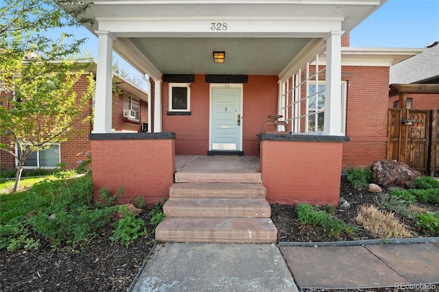 328 S Lincoln St, Denver, CO 80209 - property entrance featuring covered porch, brick siding, and cooling unit