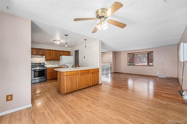 10171 W 69th Ave, Arvada, CO 80004 - kitchen featuring stainless steel range with gas cooktop, freestanding refrigerator, a textured ceiling, a peninsula, and light wood-style flooring