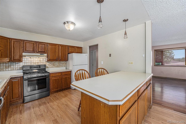 10171 W 69th Ave, Arvada, CO 80004 - kitchen with gas range, freestanding refrigerator, brown cabinets, light wood-style flooring, and light countertops