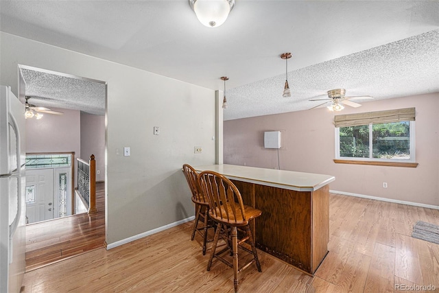 10171 W 69th Ave, Arvada, CO 80004 - kitchen with a ceiling fan, a textured ceiling, light wood finished floors, freestanding refrigerator, and a peninsula