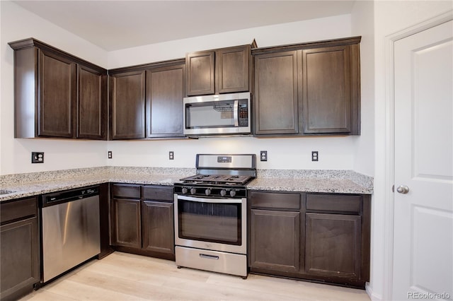 kitchen featuring light stone countertops, appliances with stainless steel finishes, light wood-type flooring, and dark brown cabinetry