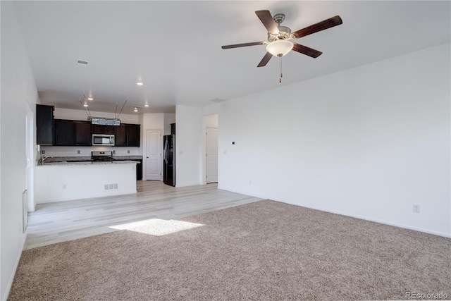 unfurnished living room featuring ceiling fan and light colored carpet