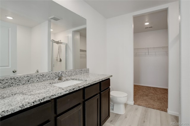 bathroom with wood-type flooring, vanity, toilet, and an enclosed shower