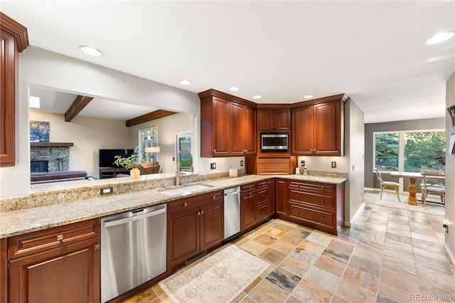 kitchen with a stone fireplace, sink, appliances with stainless steel finishes, beamed ceiling, and light stone countertops