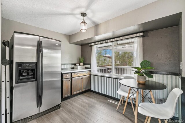 4475 London Ln, Colorado Springs, CO 80916 - kitchen featuring hanging light fixtures, light countertops, a textured ceiling, light wood-style flooring, and stainless steel refrigerator with ice dispenser