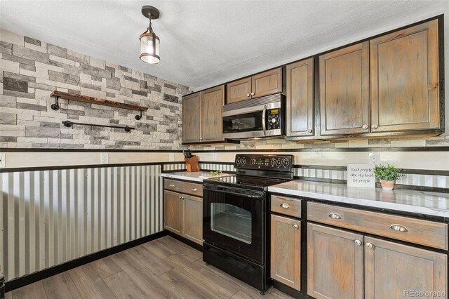 4475 London Ln, Colorado Springs, CO 80916 - kitchen featuring a textured ceiling, black electric range oven, wood finished floors, stainless steel microwave, and wallpapered walls