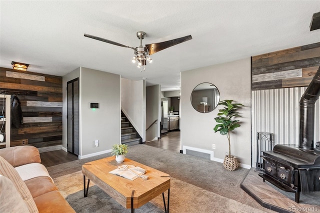 4475 London Ln, Colorado Springs, CO 80916 - living area with a wood stove, stairs, wood walls, baseboards, and a ceiling fan
