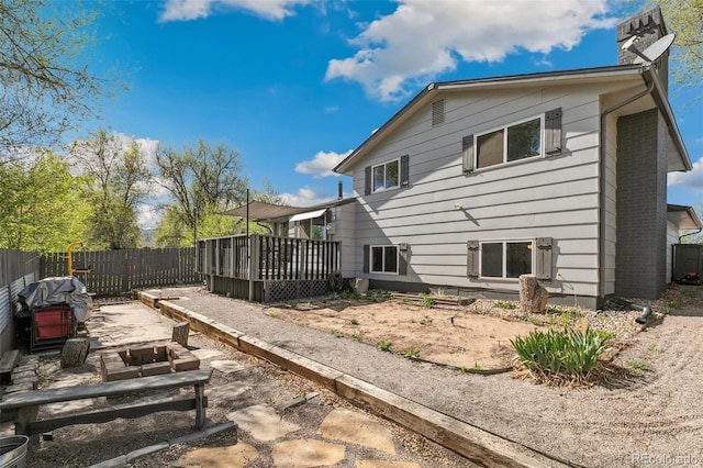 4475 London Ln, Colorado Springs, CO 80916 - rear view of house featuring fence, a wooden deck, and a chimney