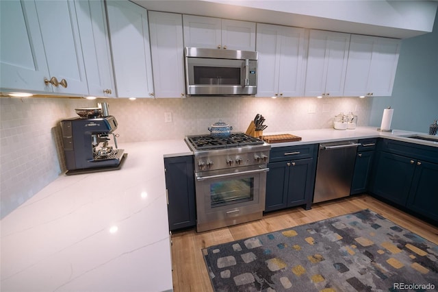 kitchen featuring white cabinets, light wood-style flooring, stainless steel appliances, and decorative backsplash