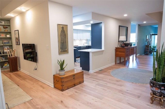 hallway featuring light wood-style floors, baseboards, and recessed lighting