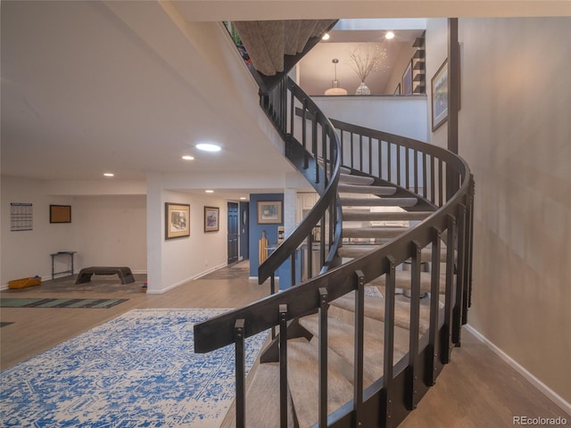 stairs featuring recessed lighting, a towering ceiling, baseboards, and wood finished floors